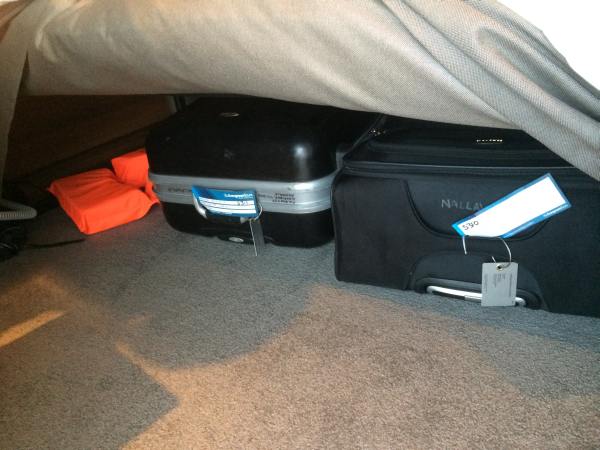 Suitcases and life vests stowed under the bed